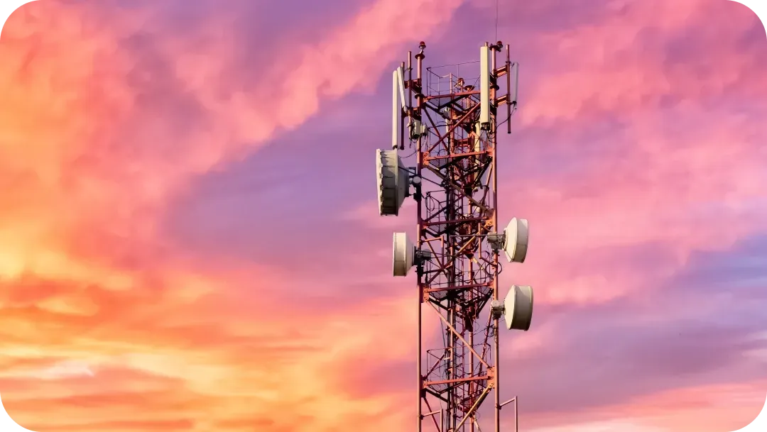 Cell tower against a vibrant pink and orange sunset sky.