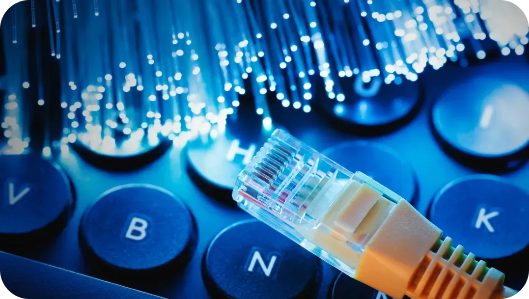 Ethernet cable and glowing fiber optic strands on a keyboard, conveying internet connectivity.
