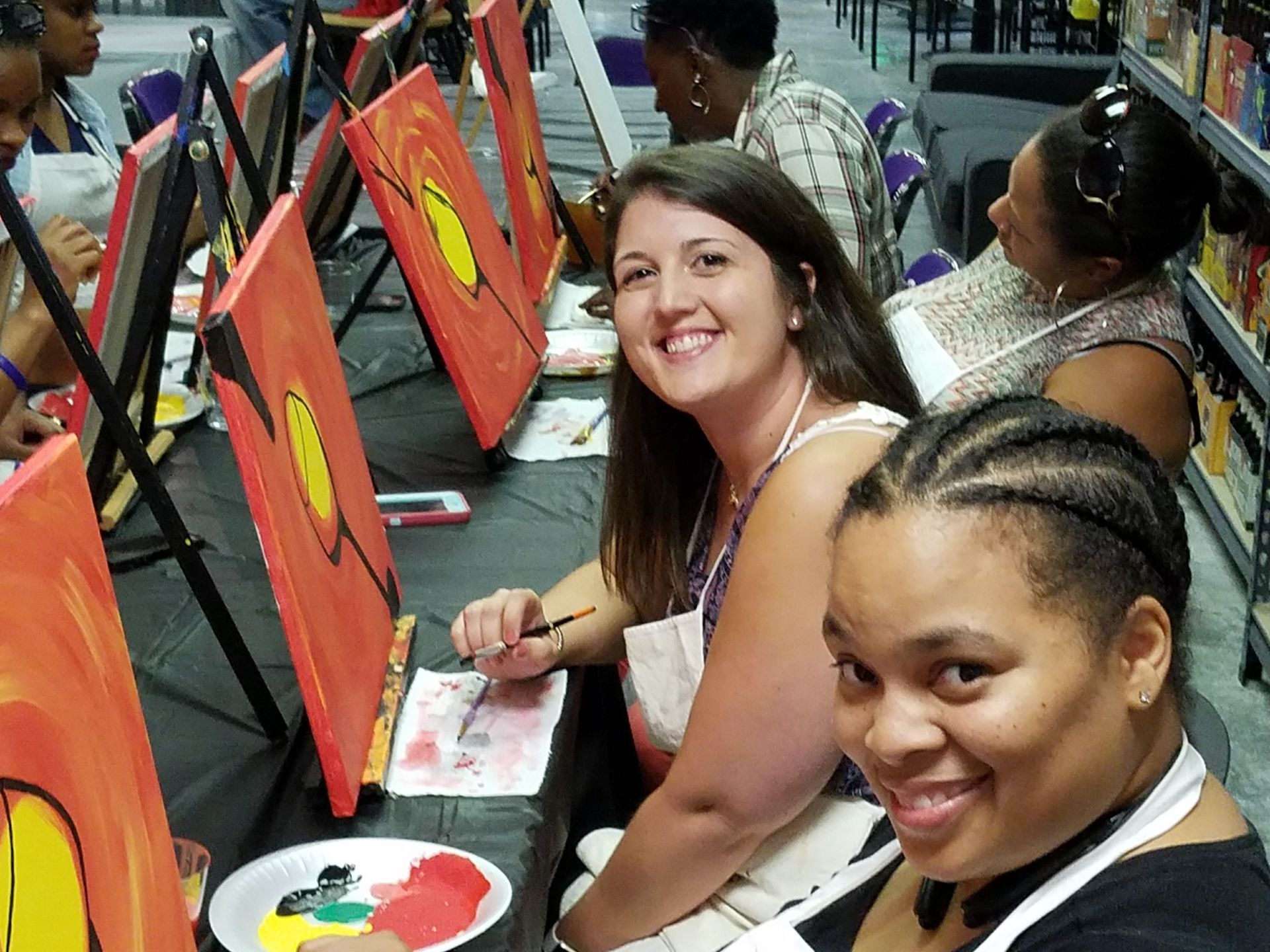 A group of women are sitting at a table painting