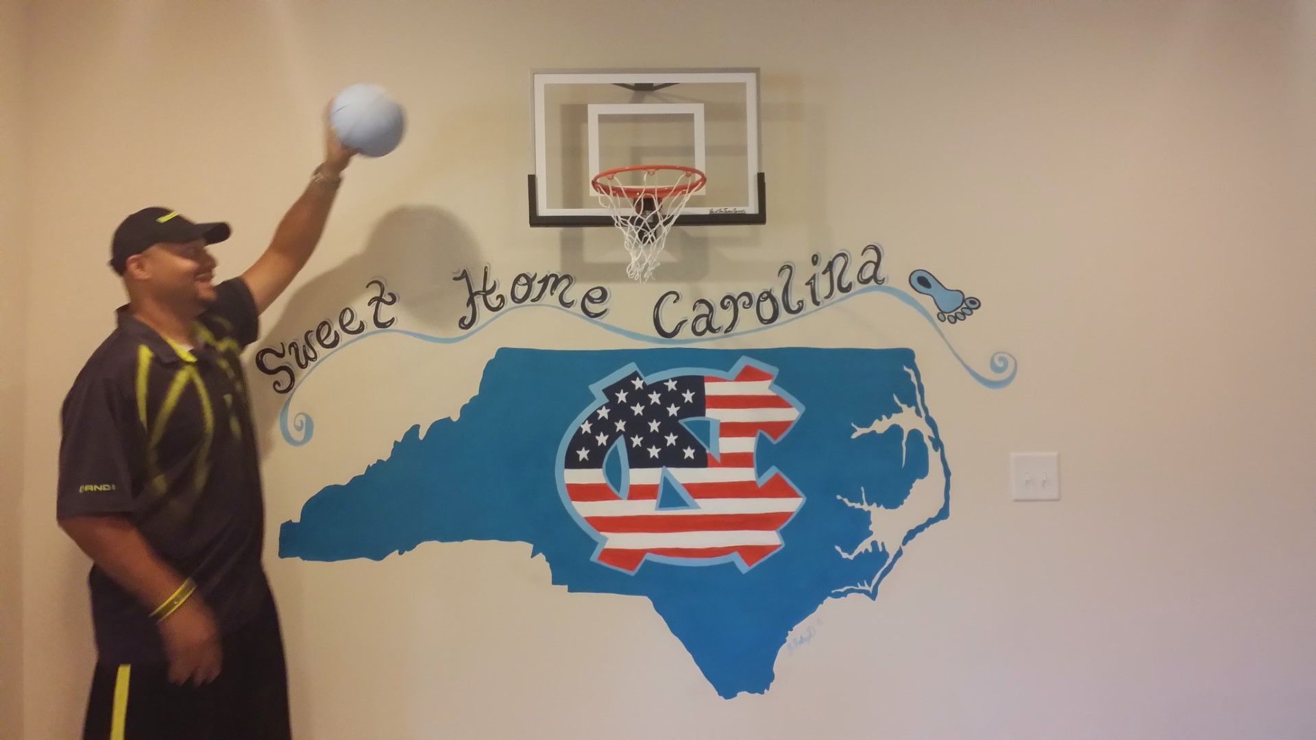 A man is throwing a ball in front of a map of north carolina
