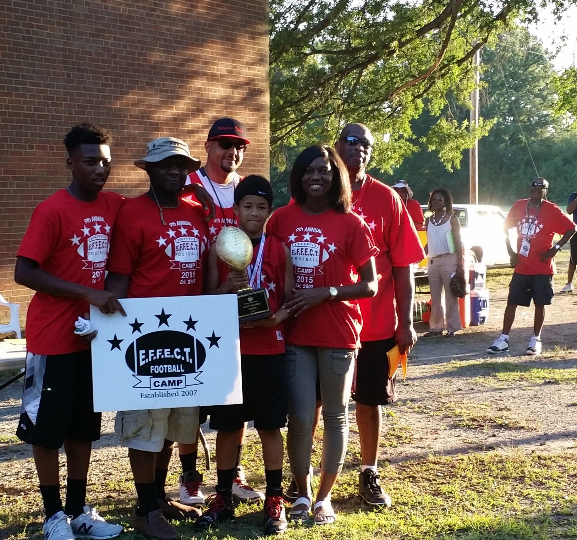 A group of people in red shirts holding a sign that says perfect summer camp