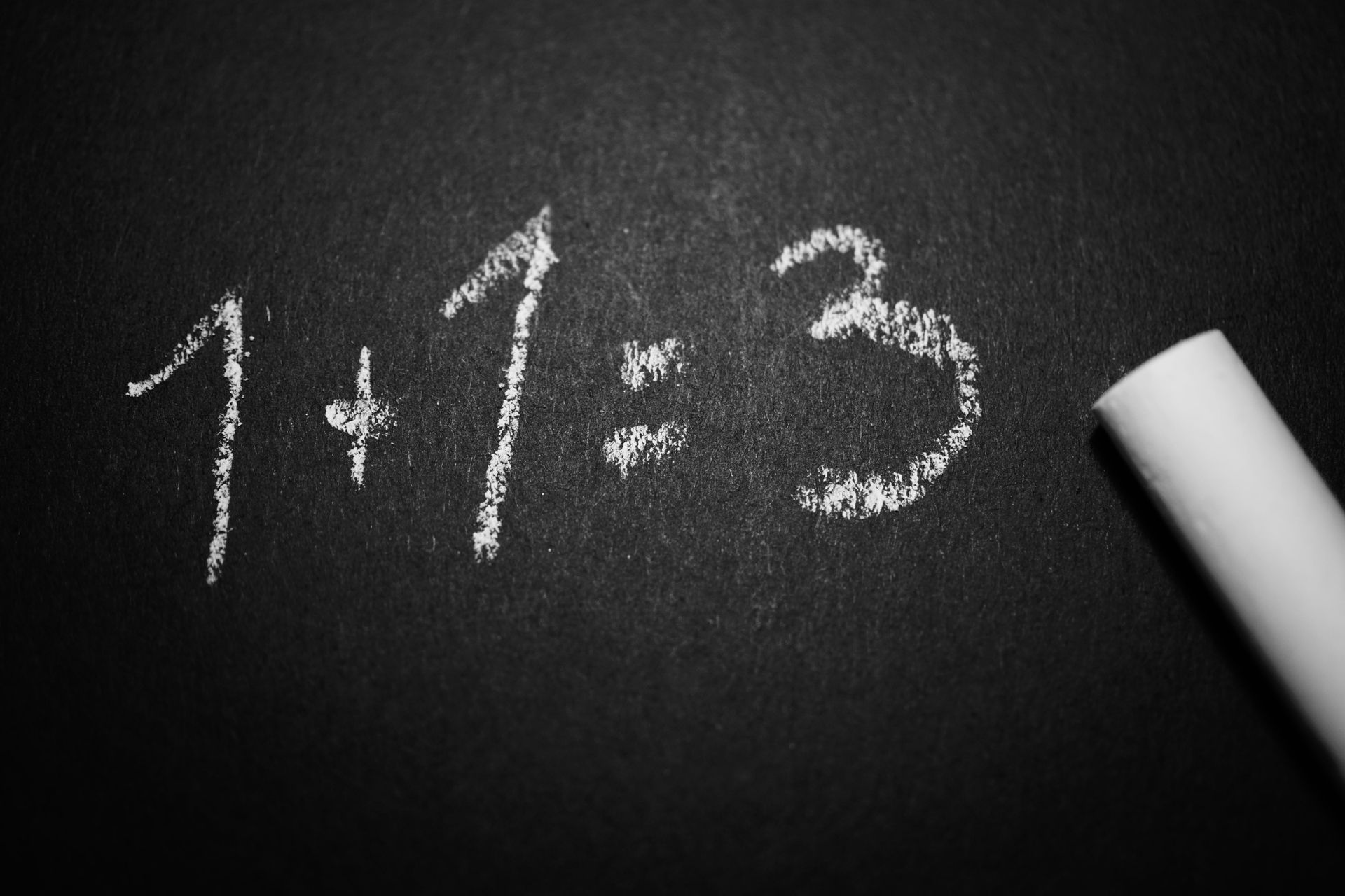 Numbers written on a black chalkboard. 1+1=3