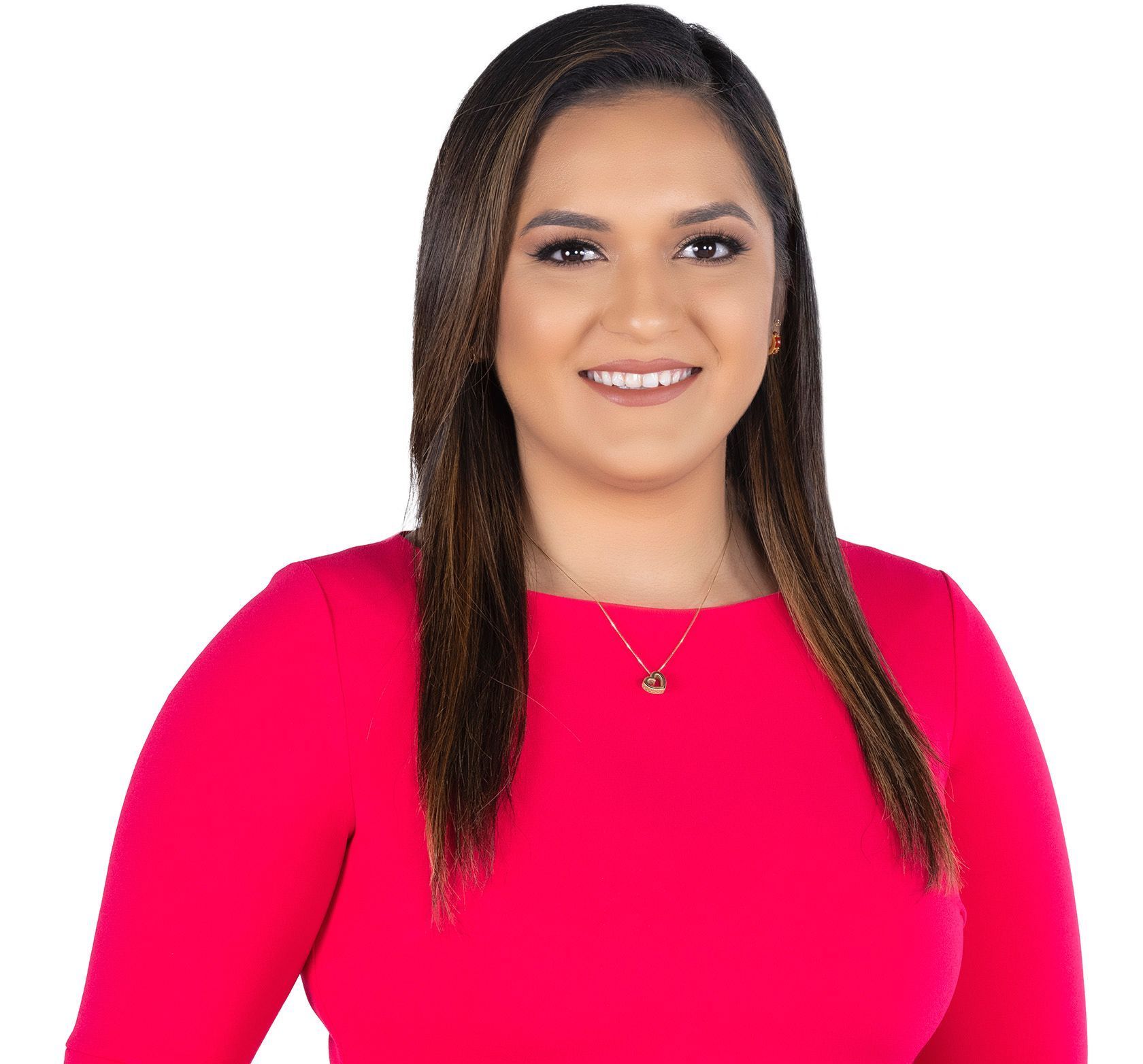 A woman wearing a pink shirt and a necklace smiles for the camera