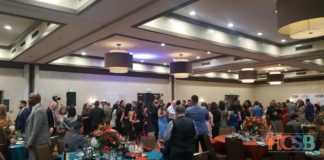 A large room filled with people standing around tables.