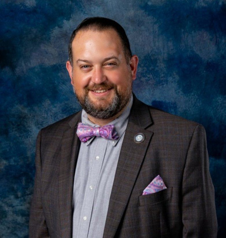 A man wearing a suit and a purple bow tie