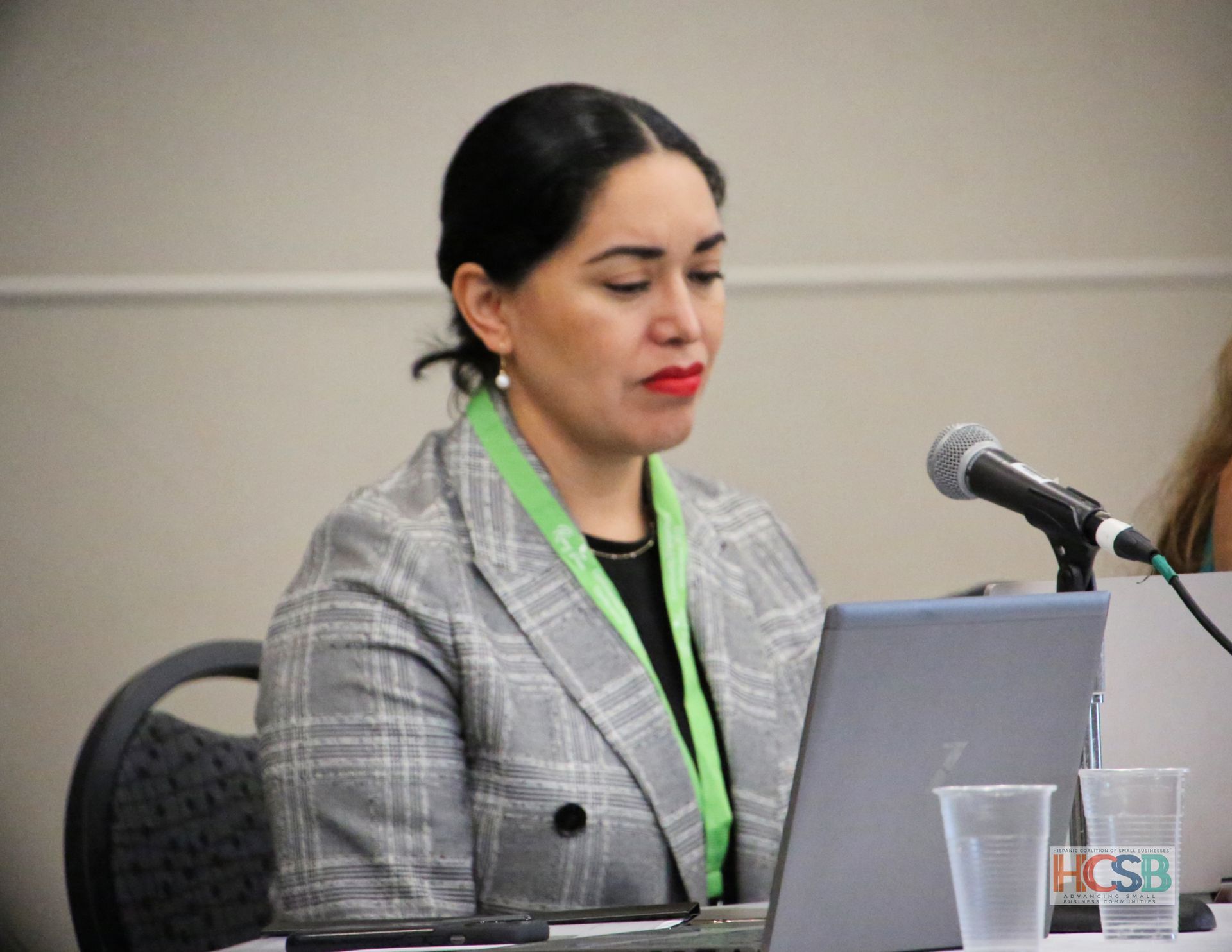 A woman is sitting at a table with a laptop and a microphone.