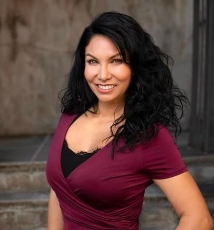 A woman in a purple shirt is smiling for the camera.