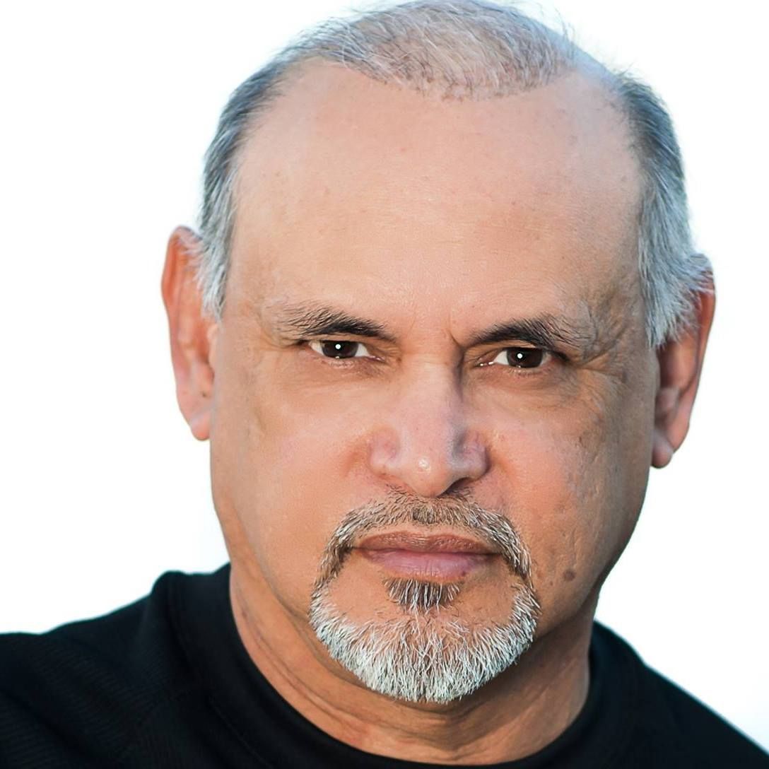 A bald man with a beard is wearing a black shirt