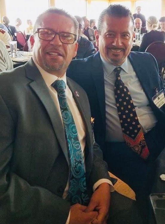 Two men in suits and ties are posing for a picture.