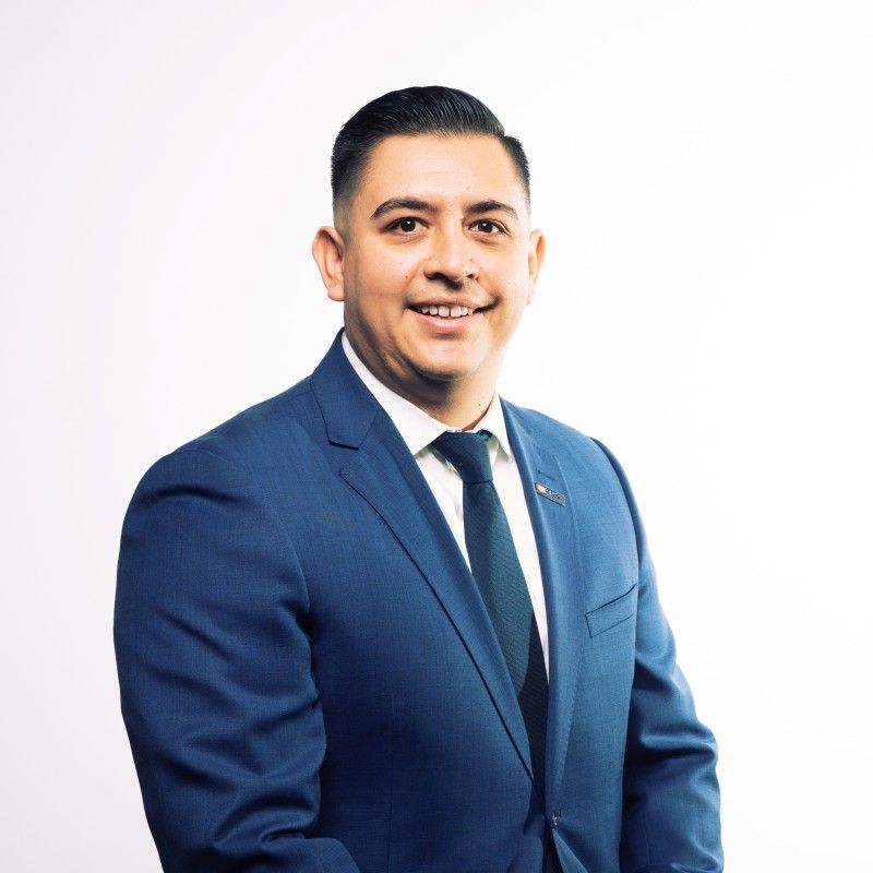 A man in a blue suit and tie is smiling for the camera.