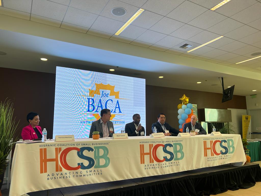 A group of people sitting at a table with a sign that says hcsb on it