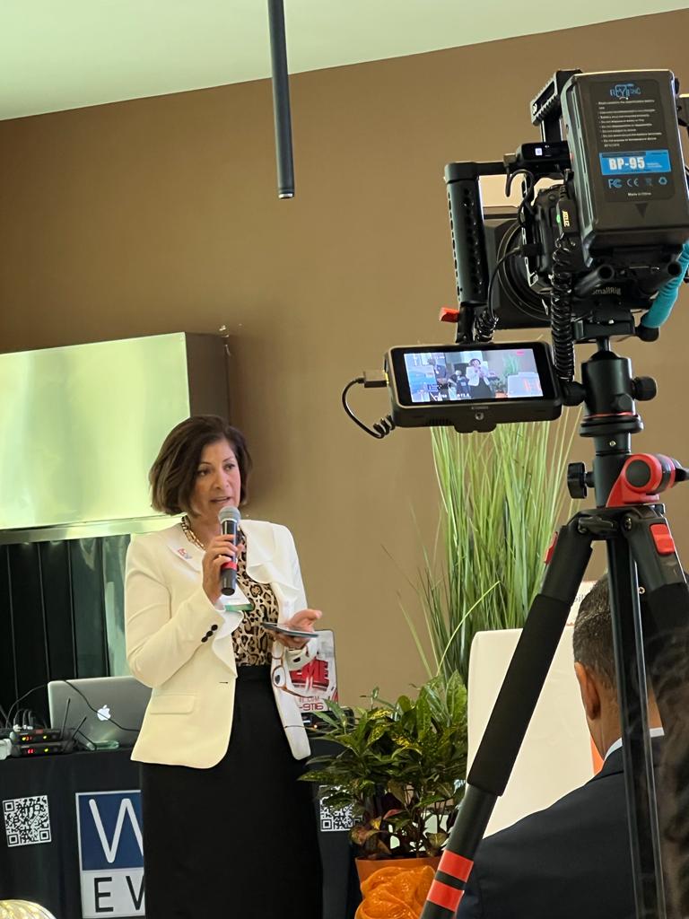 A woman is speaking into a microphone in front of a camera.