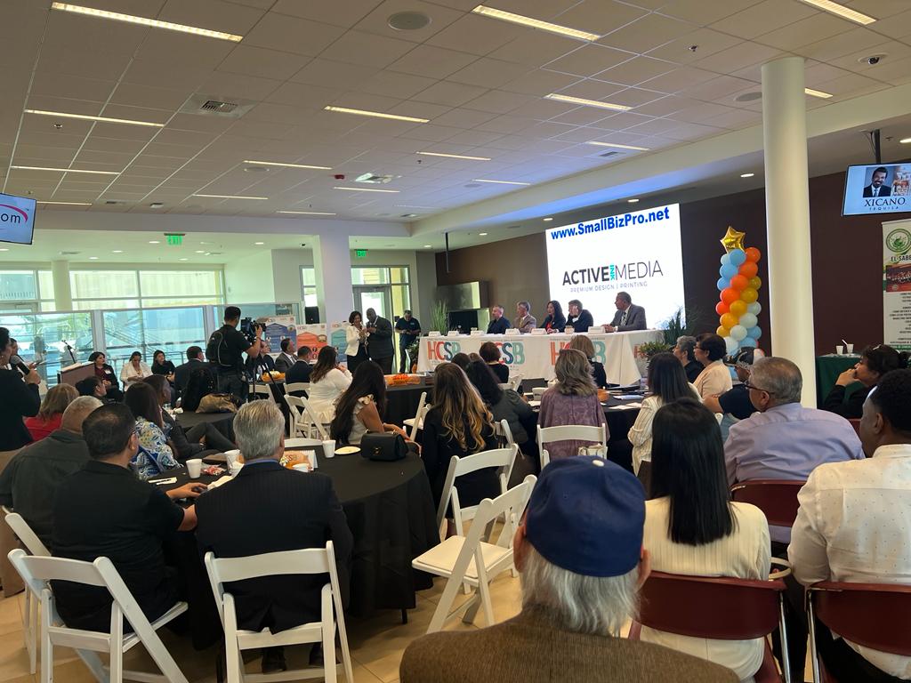 A large group of people are sitting at tables and chairs in a room.