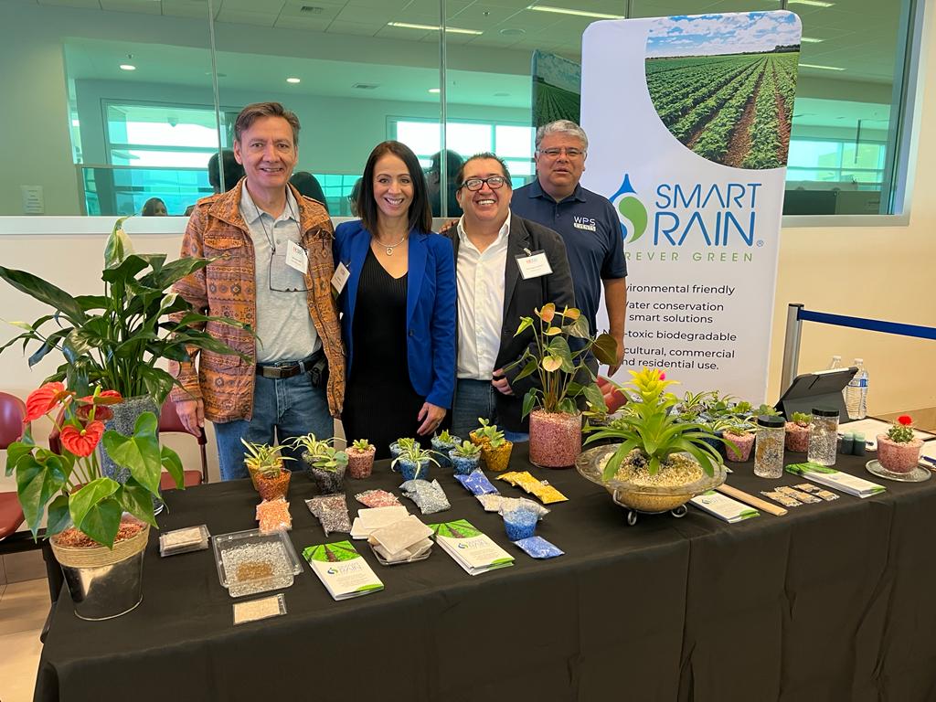 A group of people standing around a table with plants on it.