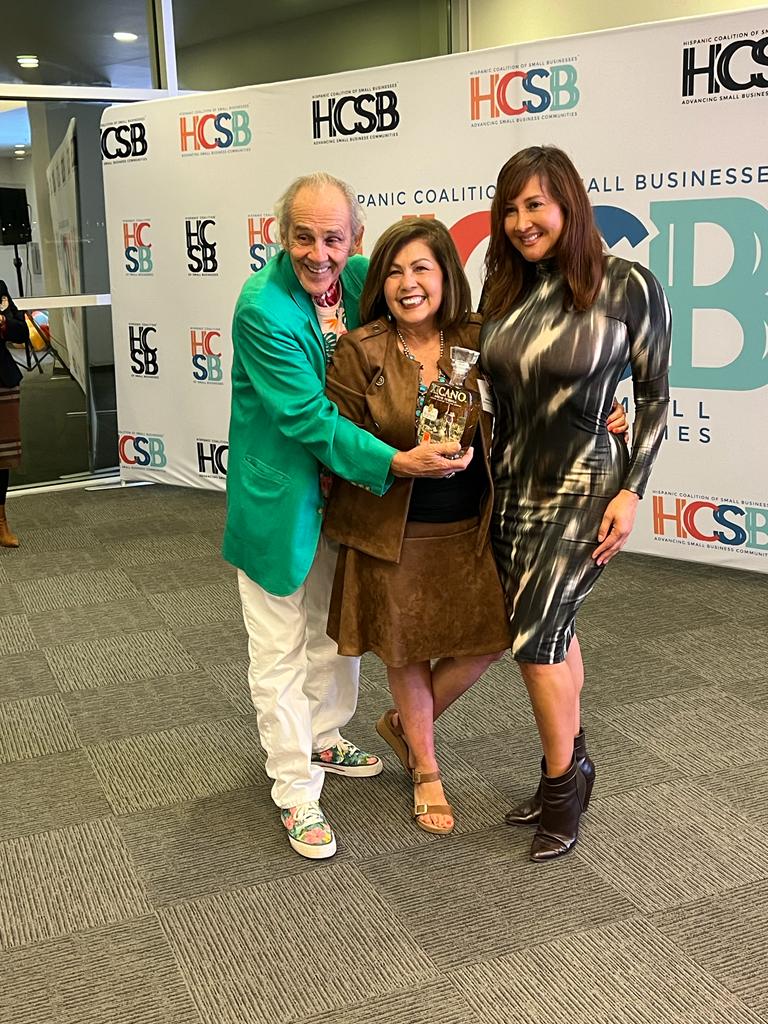 A man and two women are standing next to each other holding a trophy.