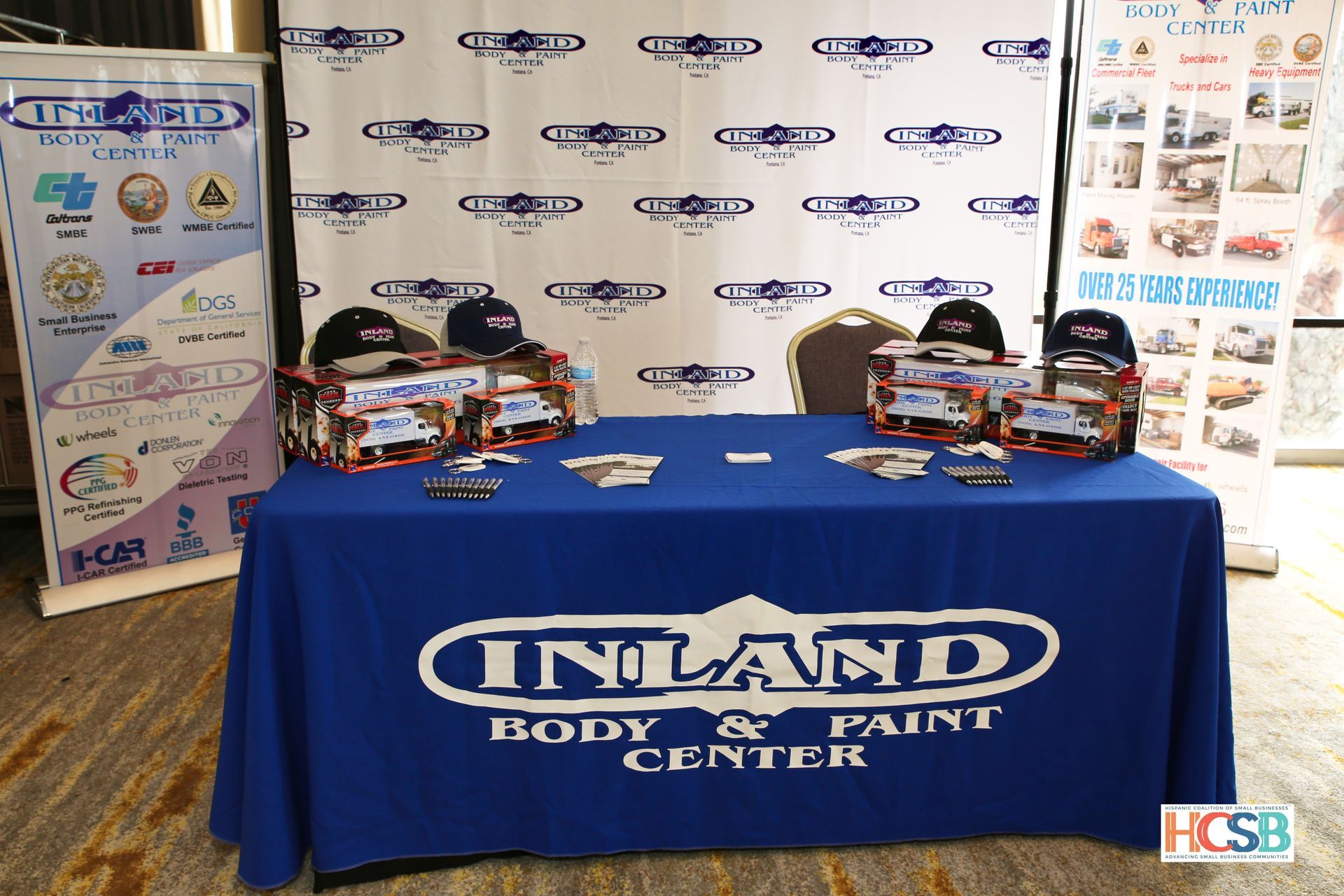 A table with a blue table cloth that says inland body & paint center
