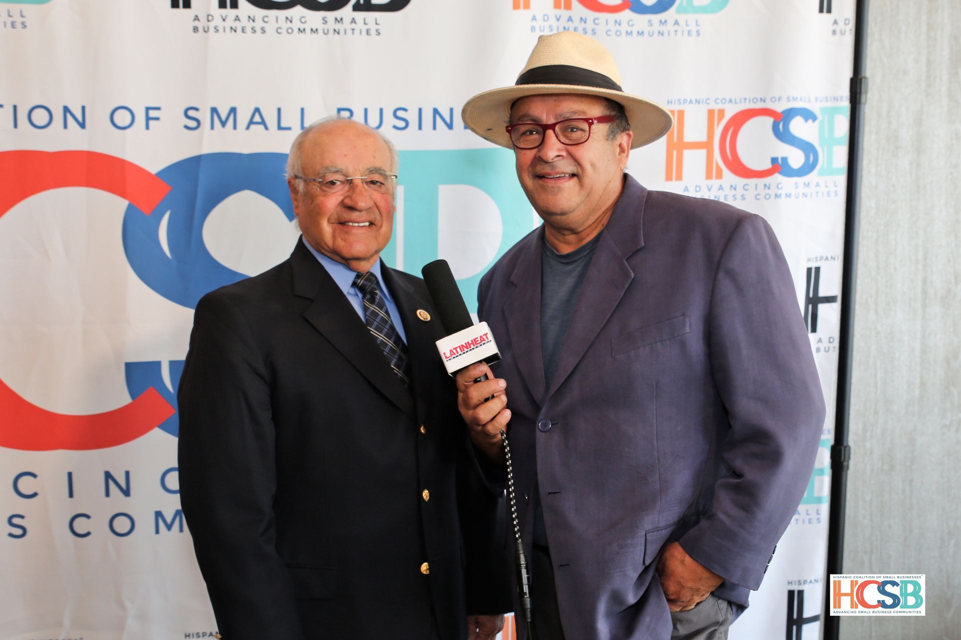 Two men are standing in front of a hcsb banner