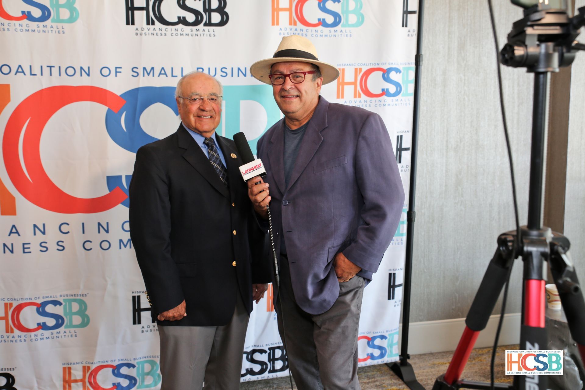 Two men are standing next to each other and one is holding a microphone.