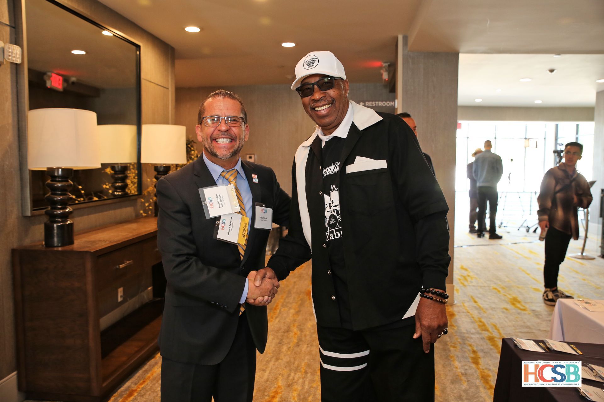 Two men are shaking hands in a hallway.