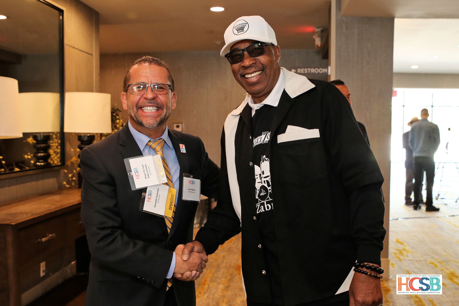 Two men are shaking hands and smiling in a room.