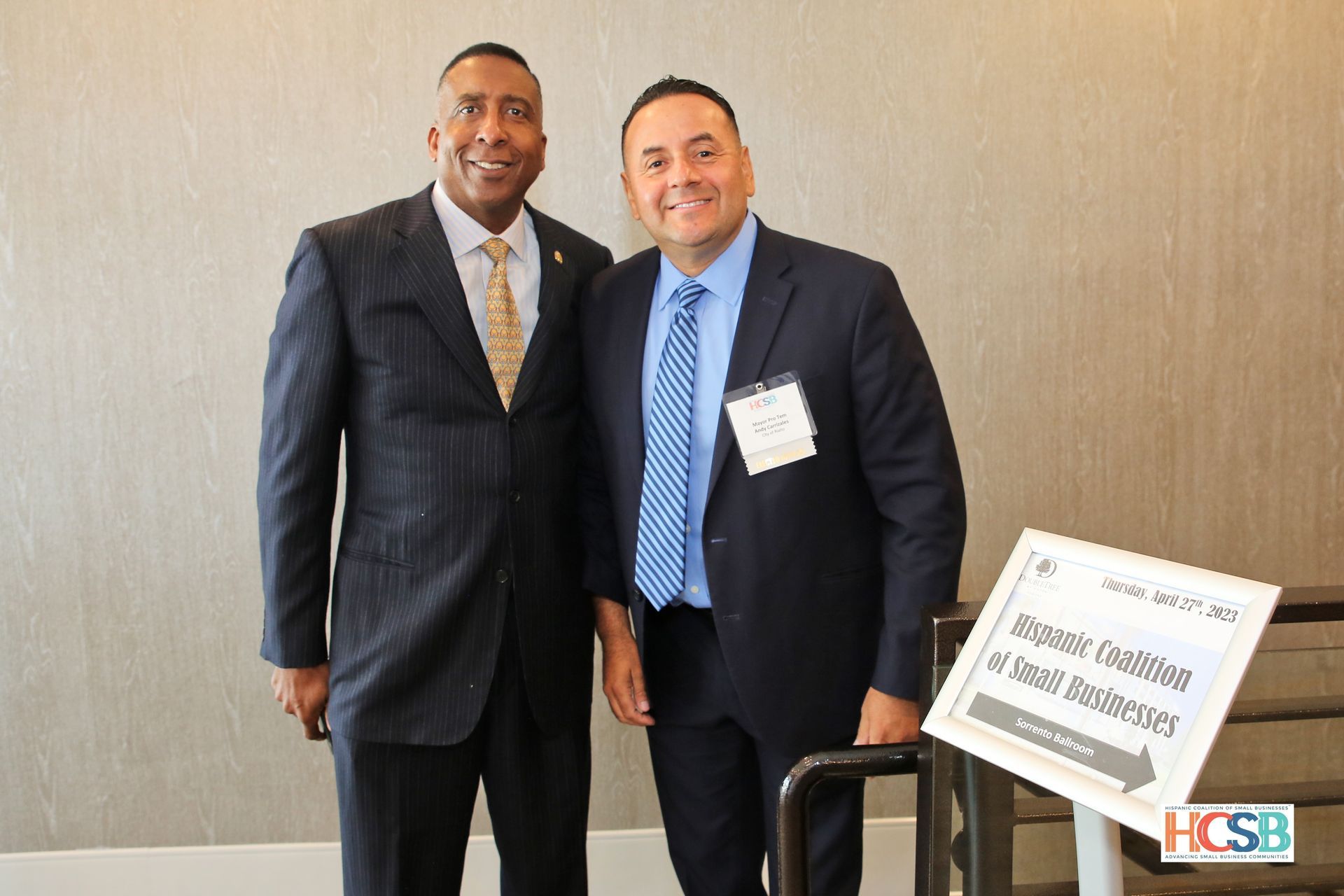 Two men in suits and ties are standing next to each other.