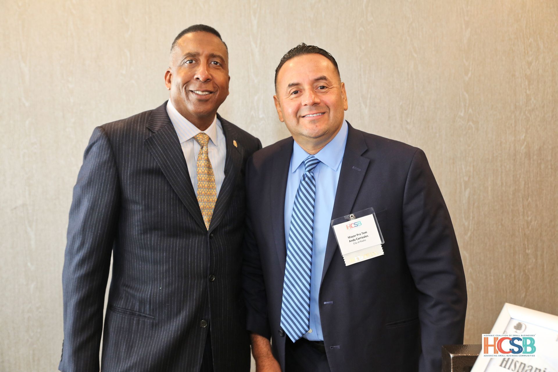 Two men in suits and ties are posing for a picture.