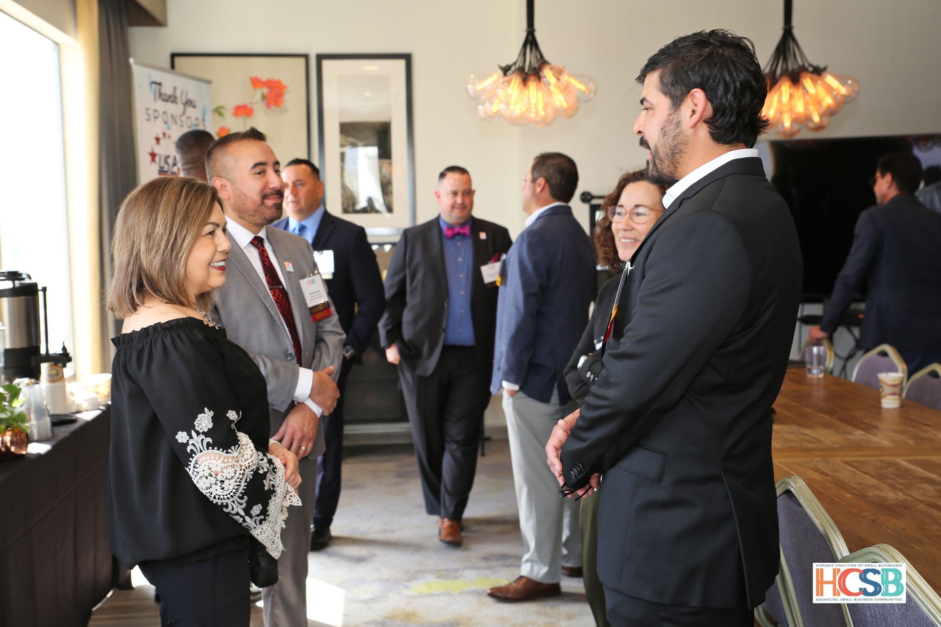 A group of people are standing in a room talking to each other.