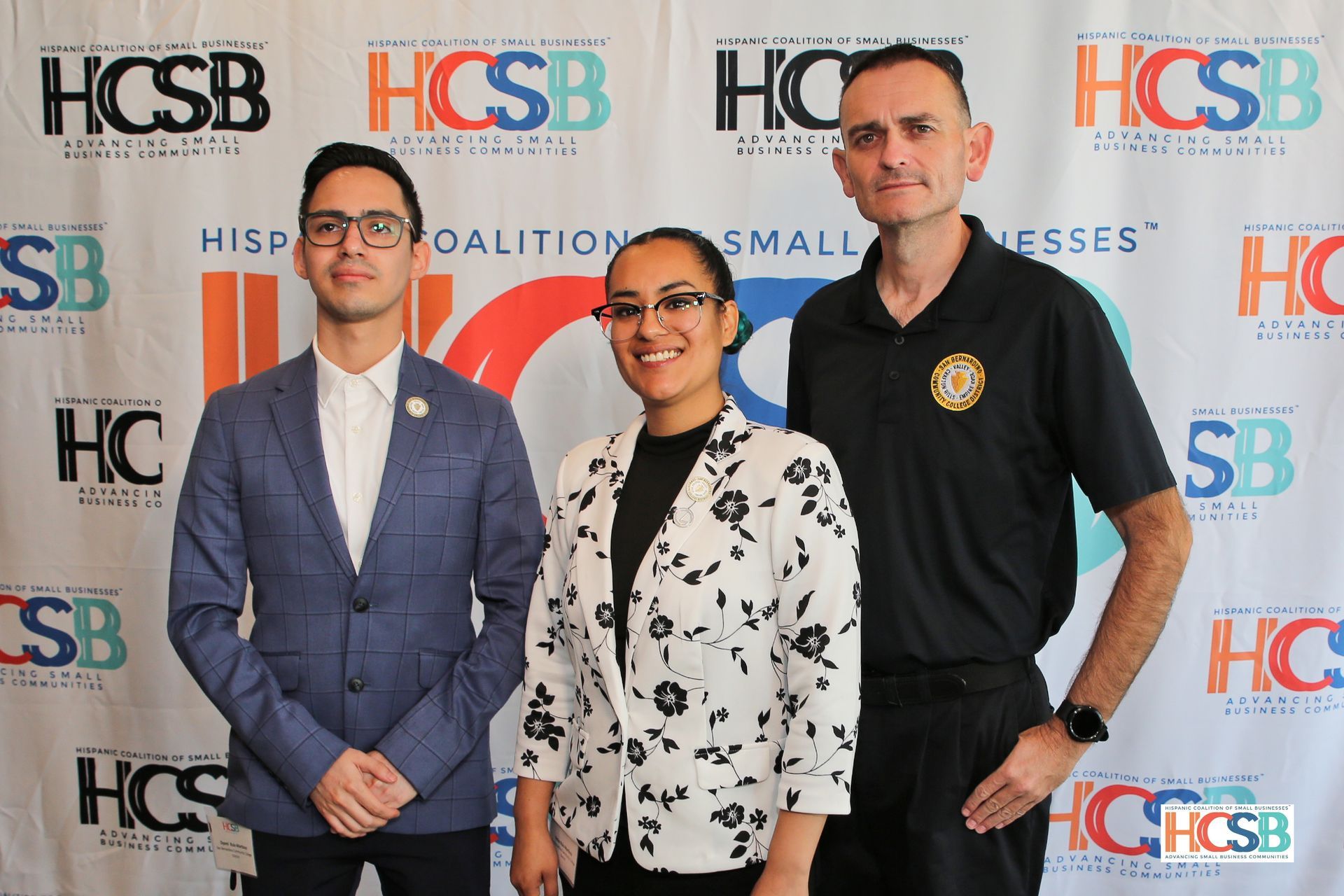 Three people standing in front of a hcsb banner