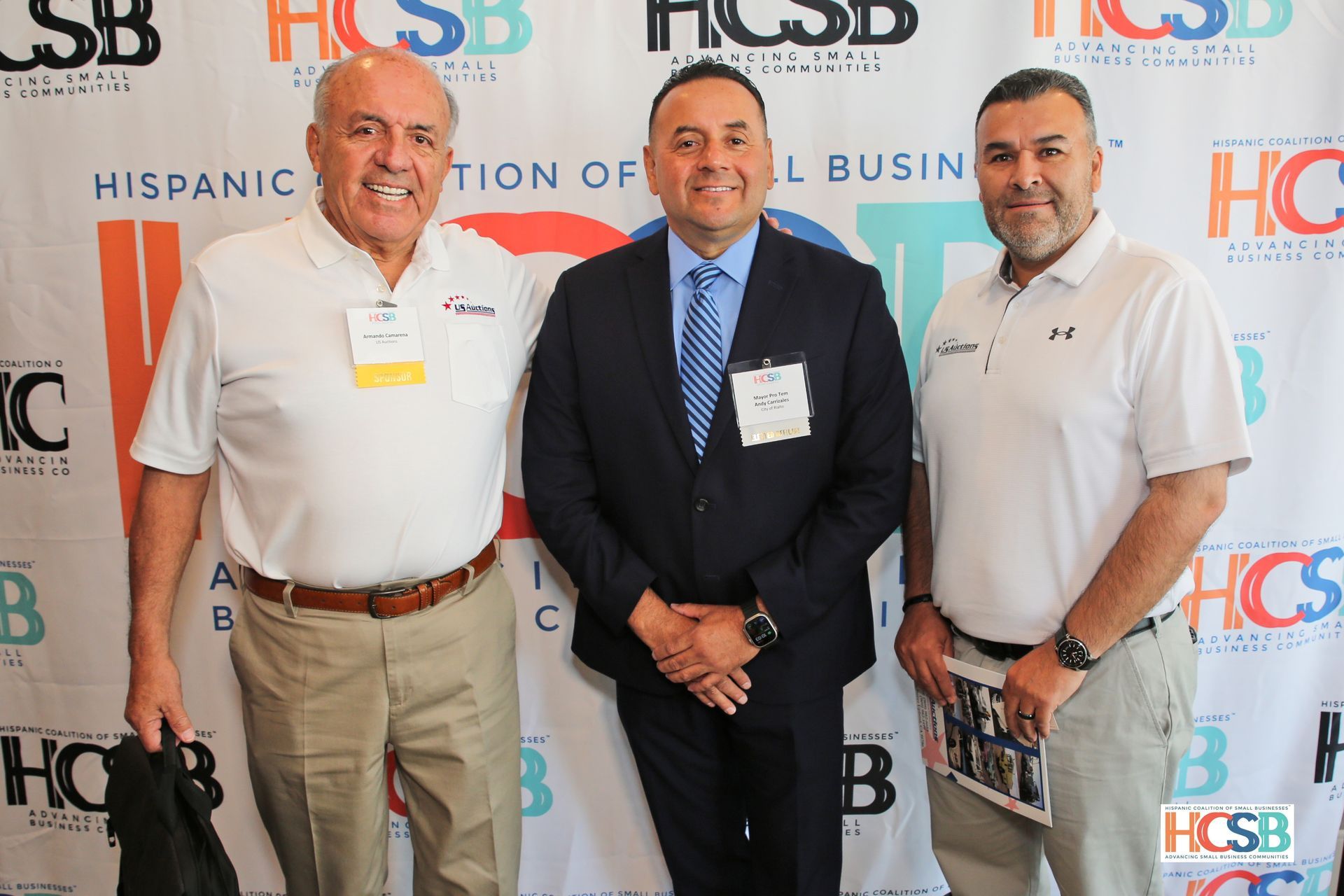Three men are posing for a picture in front of a hcsb banner.