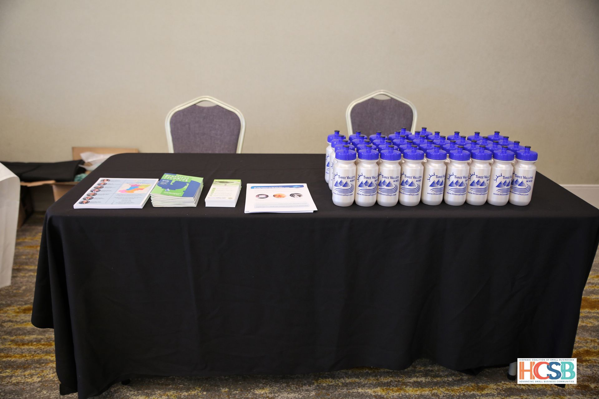 A table with a black tablecloth and a bunch of water bottles on it.