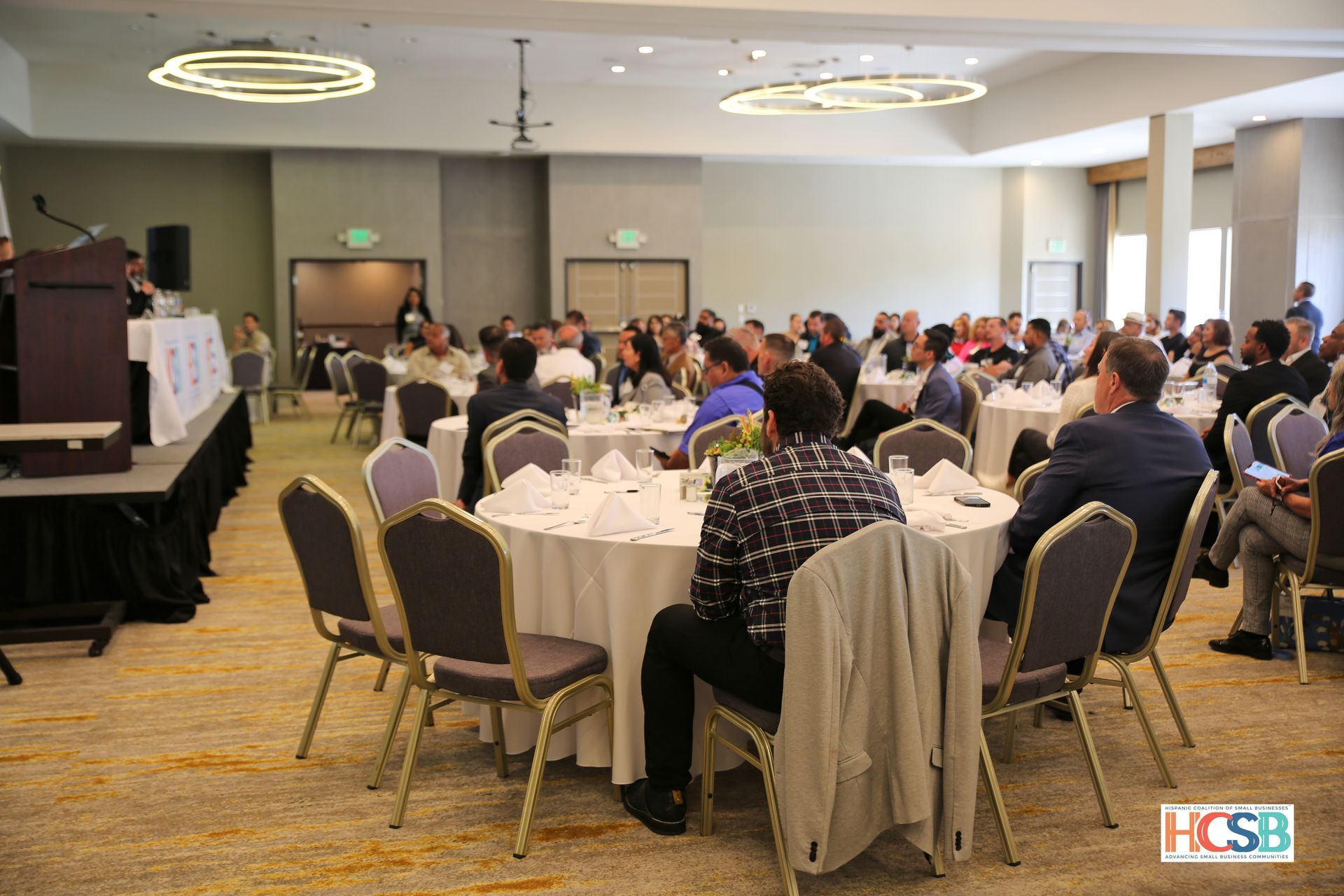 A large group of people are sitting at tables in a large room.