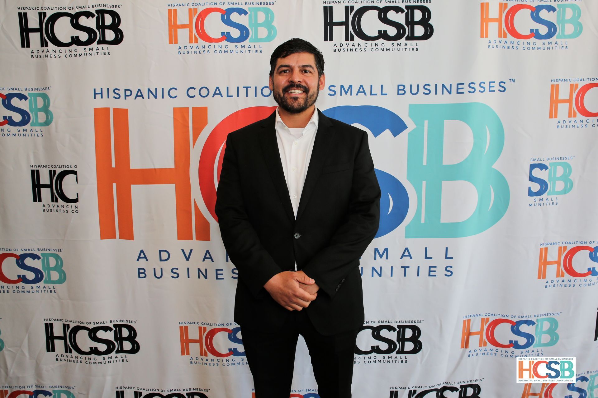 A man in a suit is standing in front of a hcsb banner.