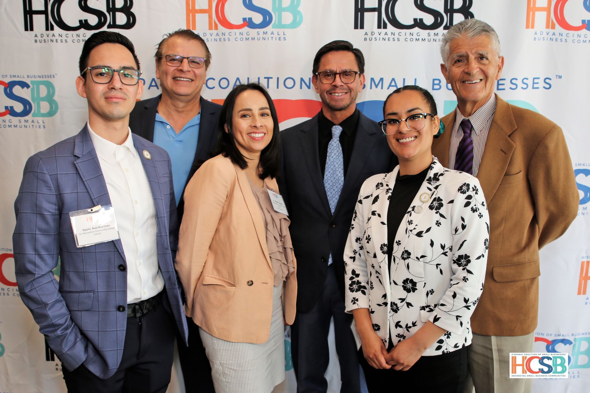 A group of people are posing for a picture in front of a hcsb banner.
