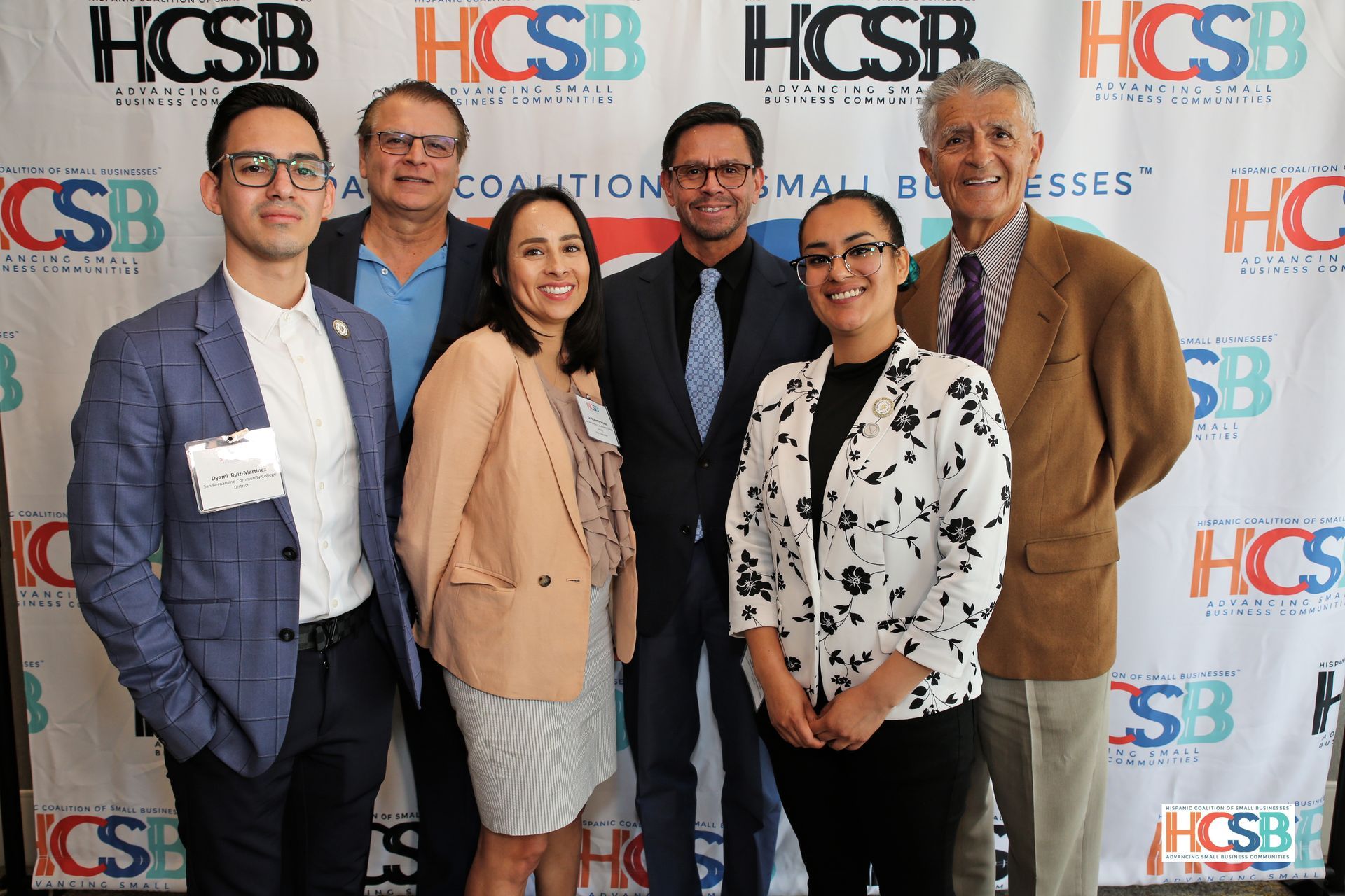 A group of people are posing for a picture in front of a hcsb banner.