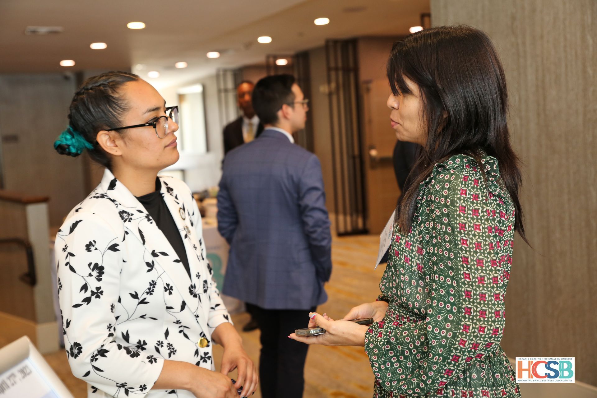 Two women are talking to each other in a hallway.