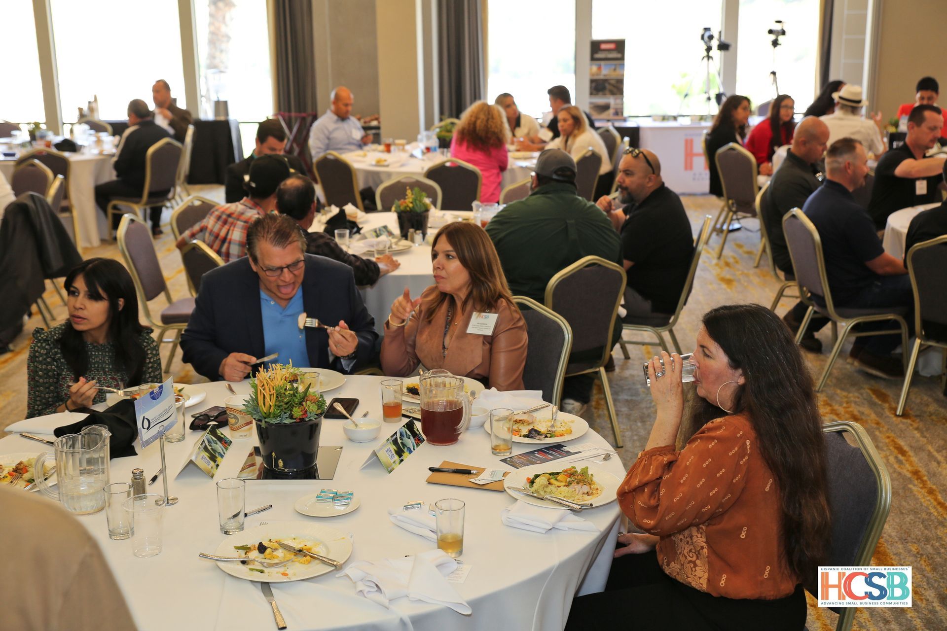 A group of people are sitting at tables in a room eating food.