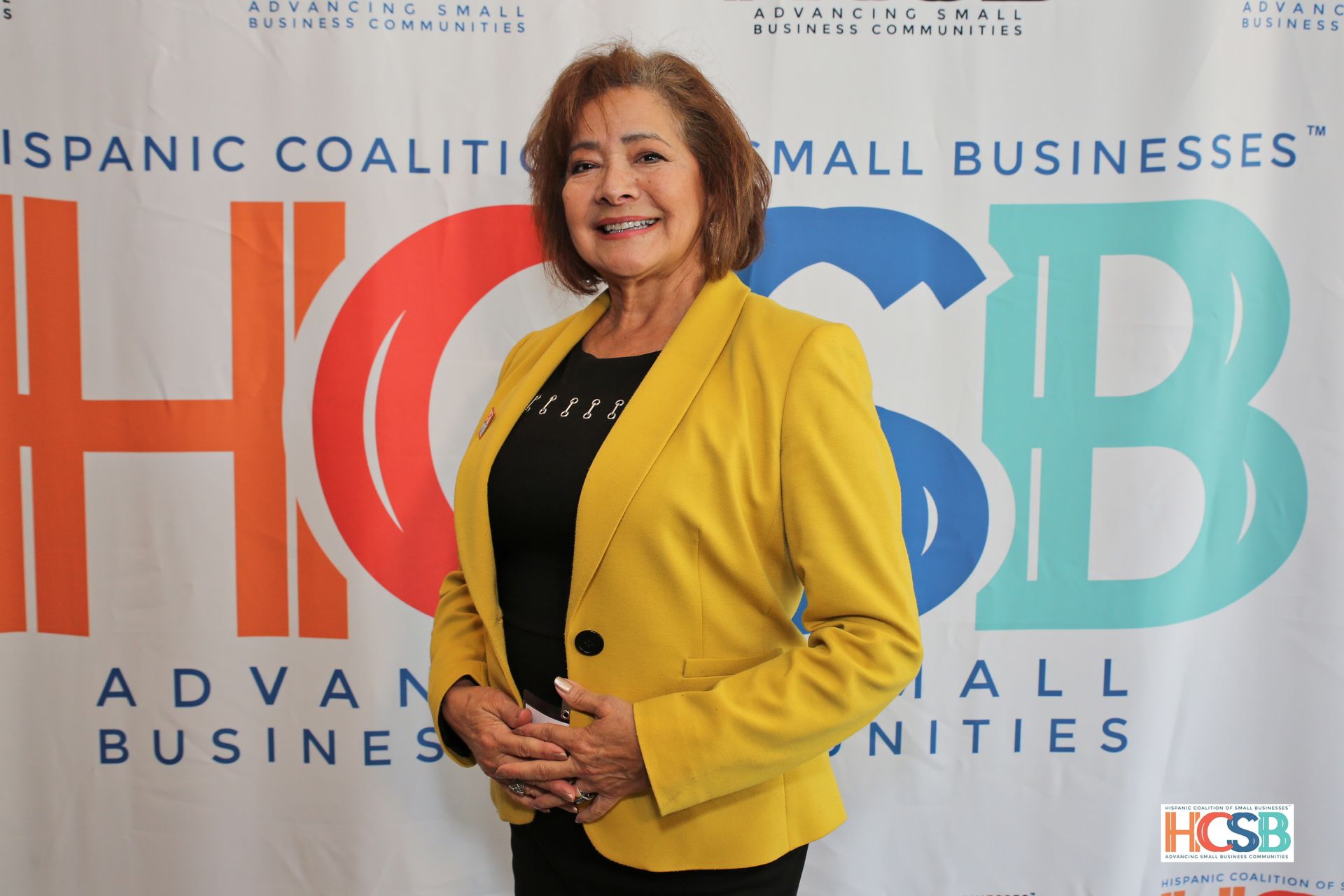 A woman in a yellow jacket is standing in front of a hcsb banner