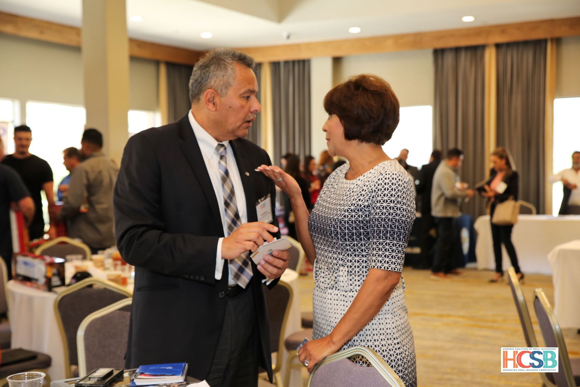 A man in a suit and tie is talking to a woman in a dress