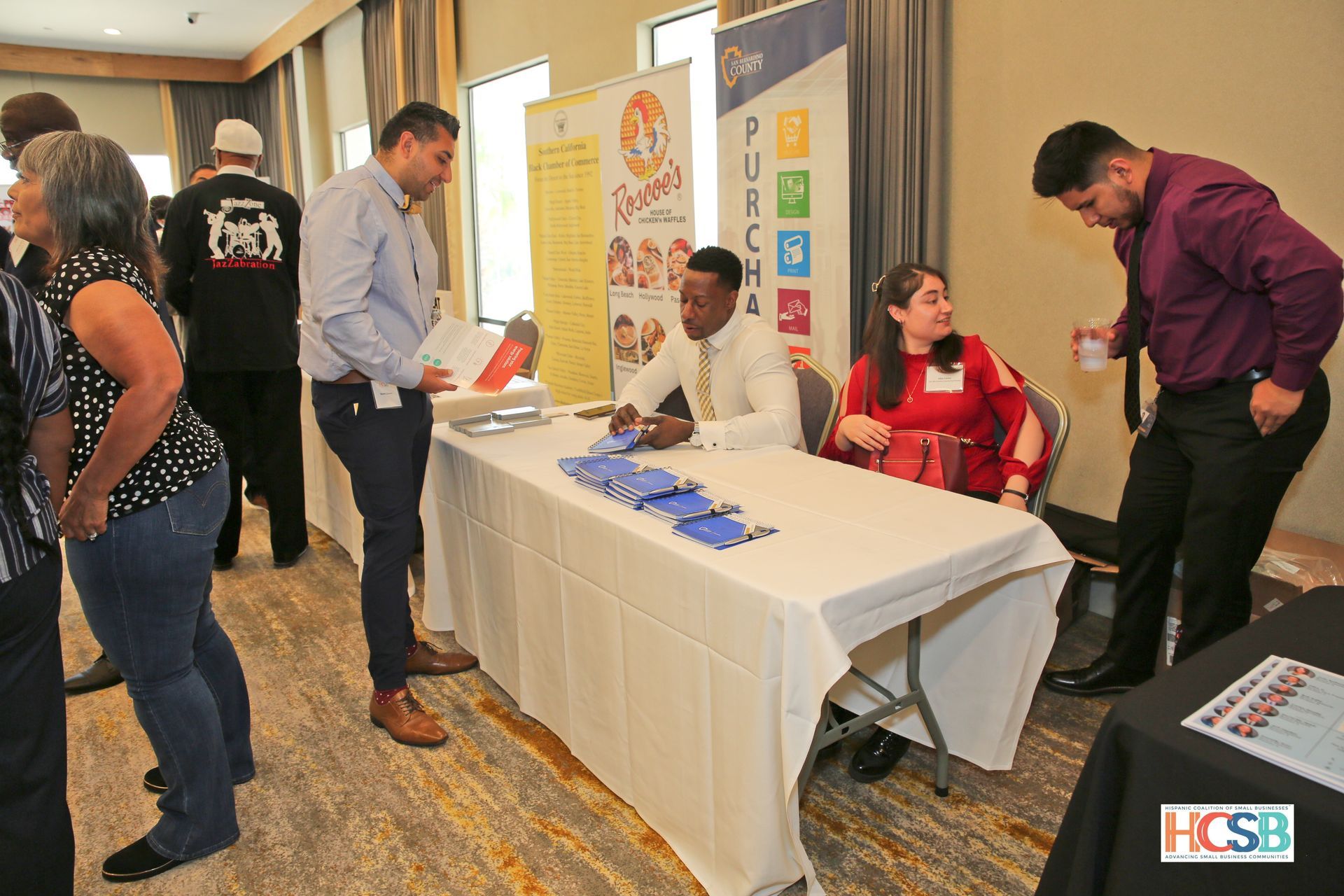A group of people are standing around a table at a job fair.