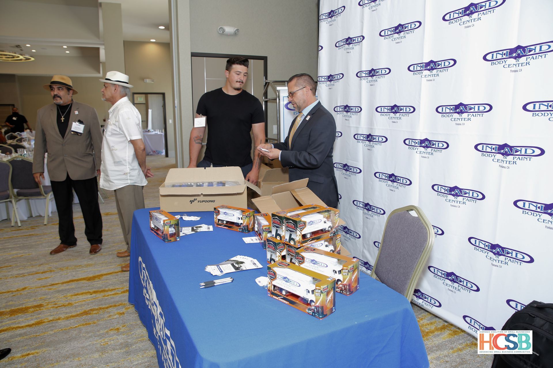 A group of men are standing around a table with boxes on it.