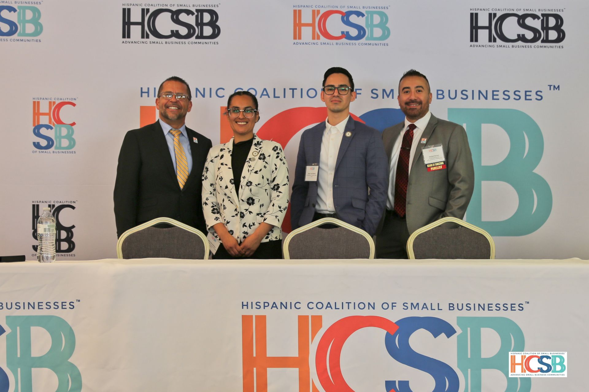A group of people are standing in front of a wall that says hispanic coalition of small businesses