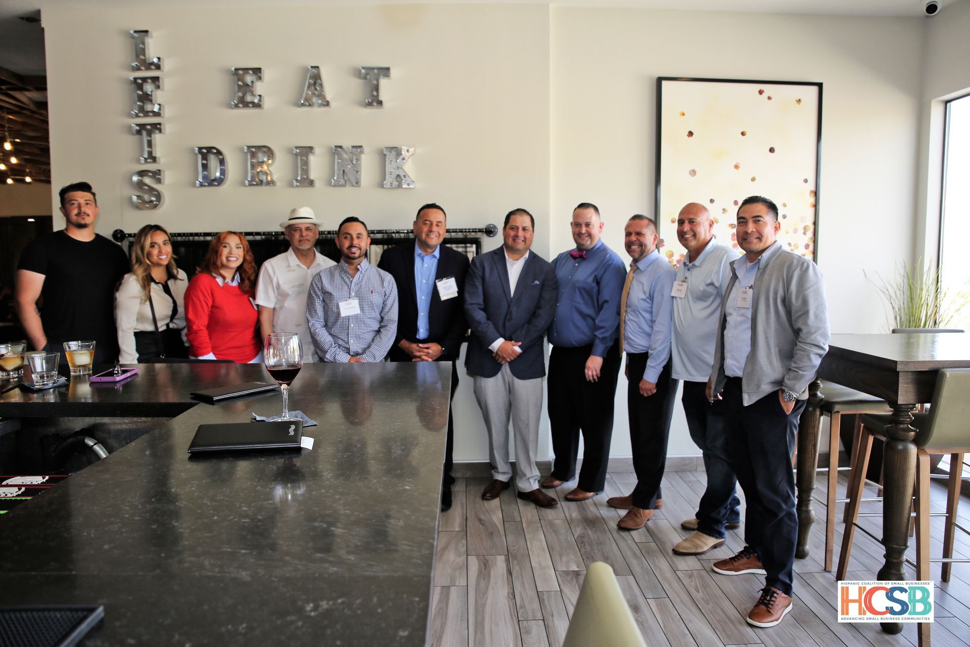 A group of people are posing for a picture in front of a sign that says eat drink.