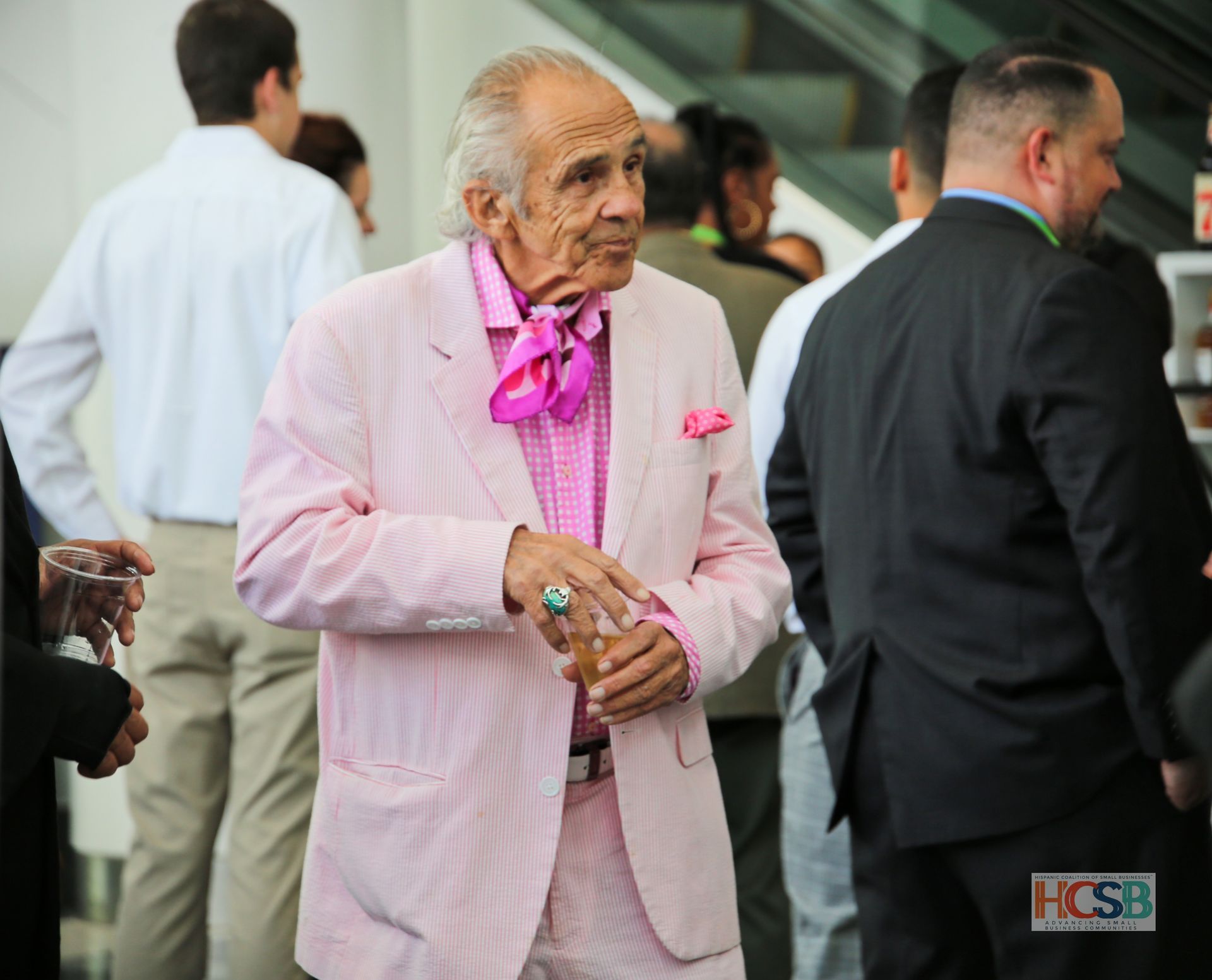 A man in a pink suit is standing in a crowd