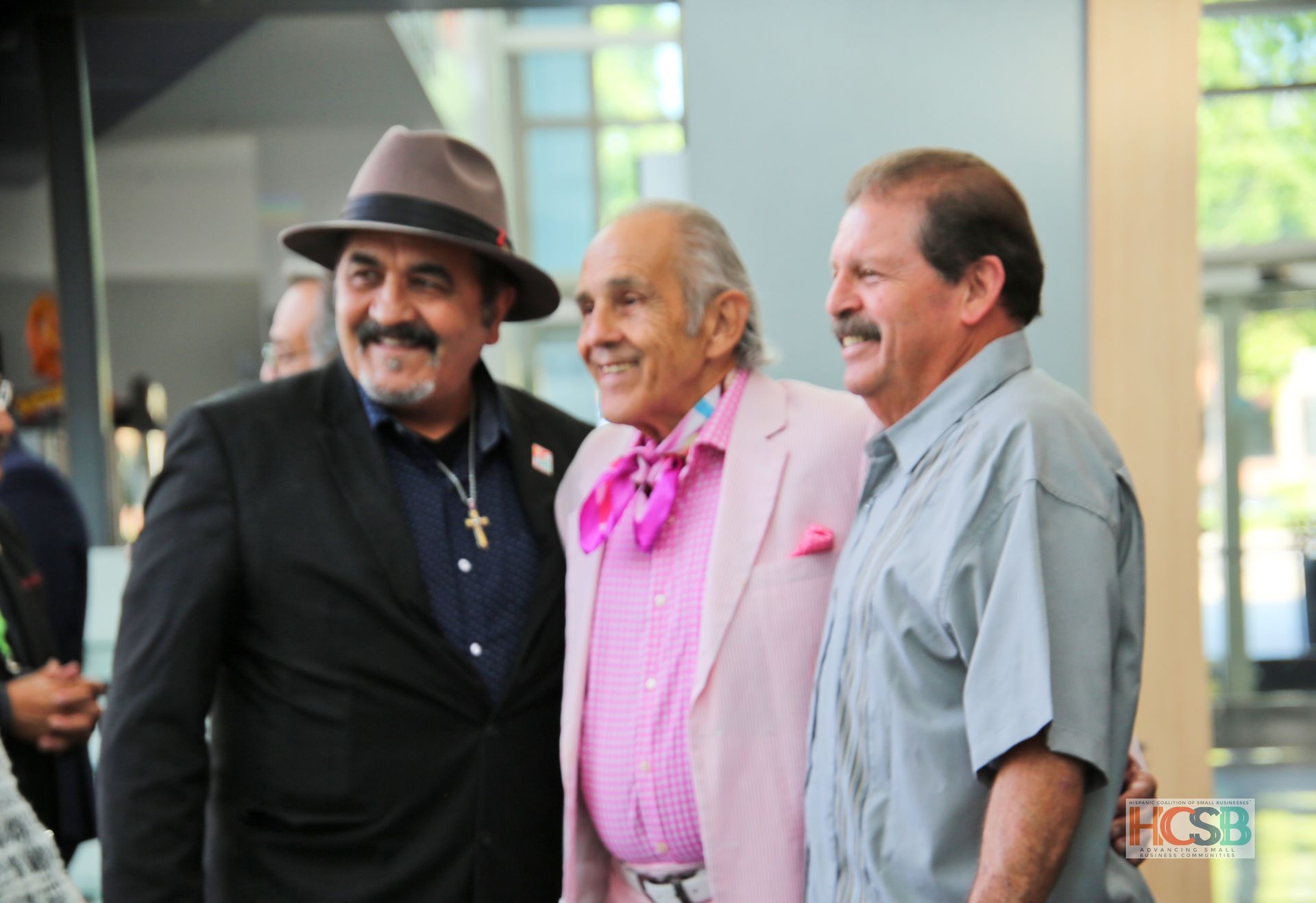 Three men are posing for a picture and one of them is wearing a hat