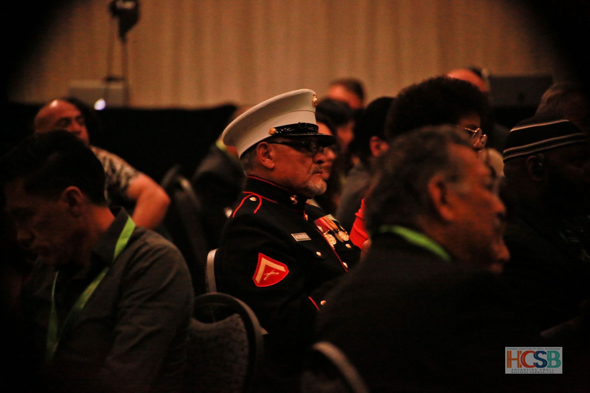 A man in a marine uniform sits in a crowd of people