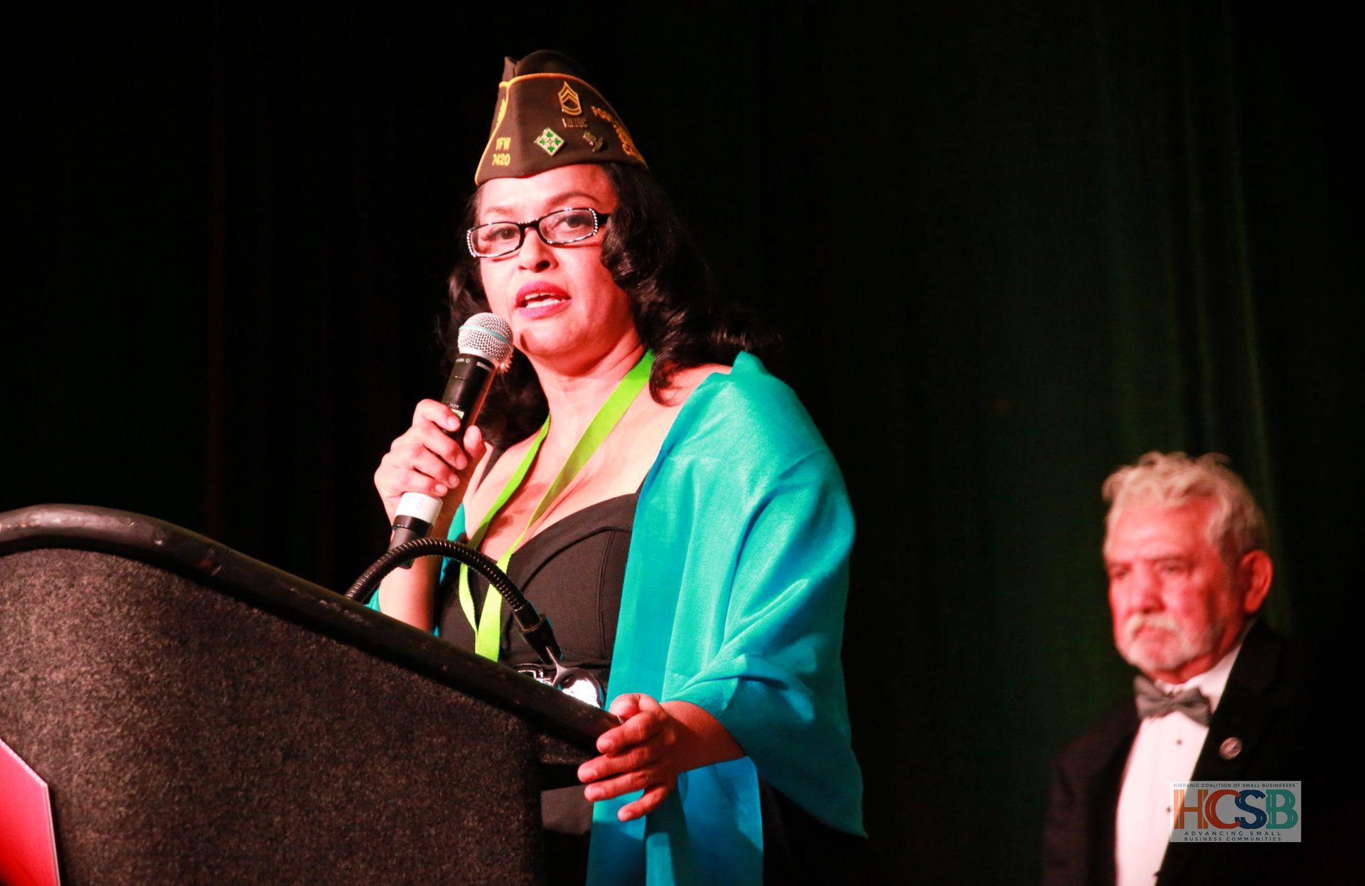A woman stands at a podium speaking into a microphone