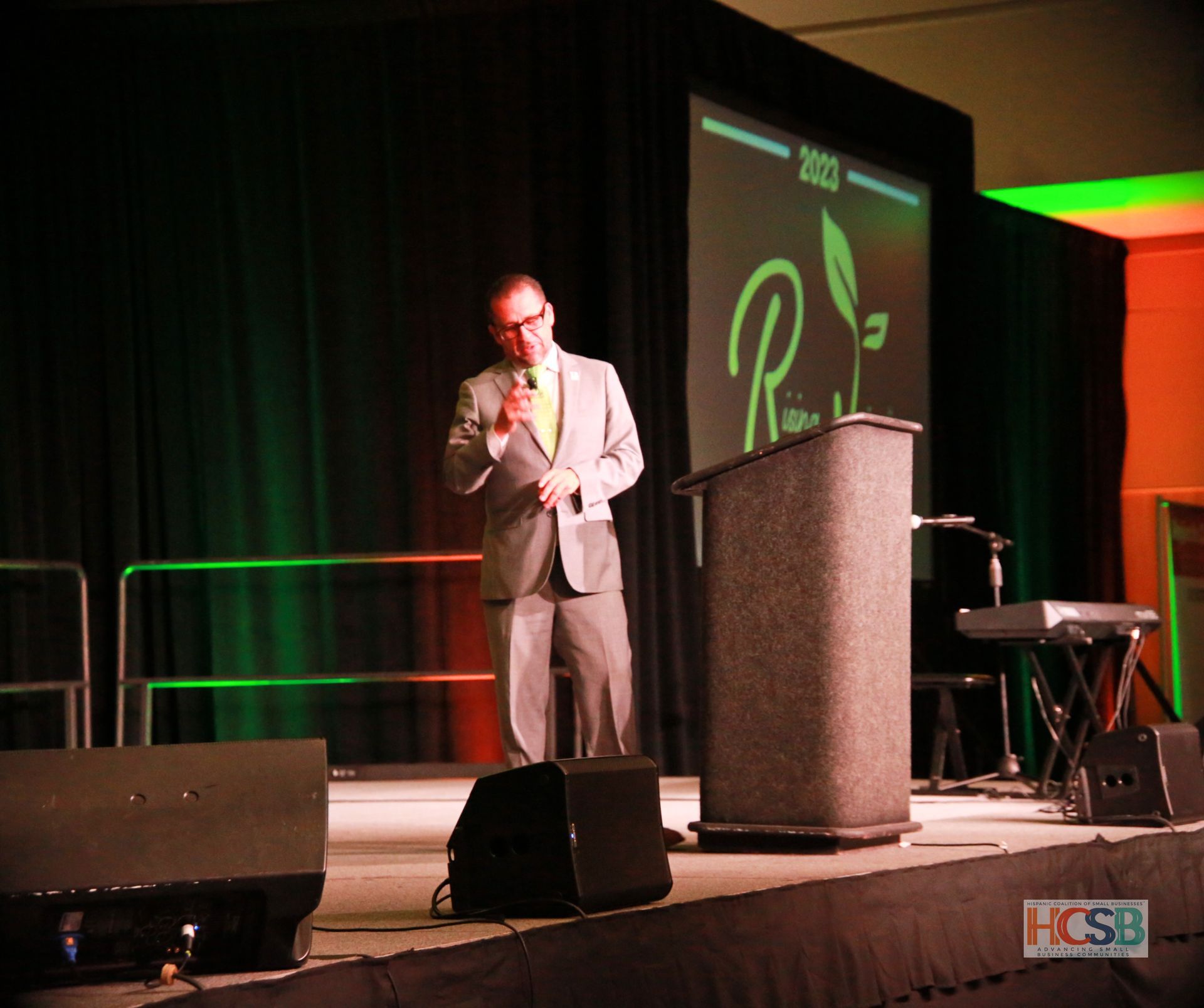A man in a suit stands on a stage giving a speech
