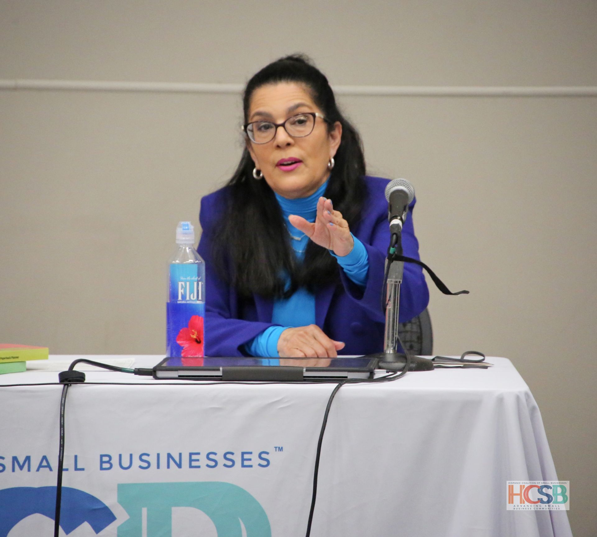 A woman sitting at a table with a bottle of fiji water