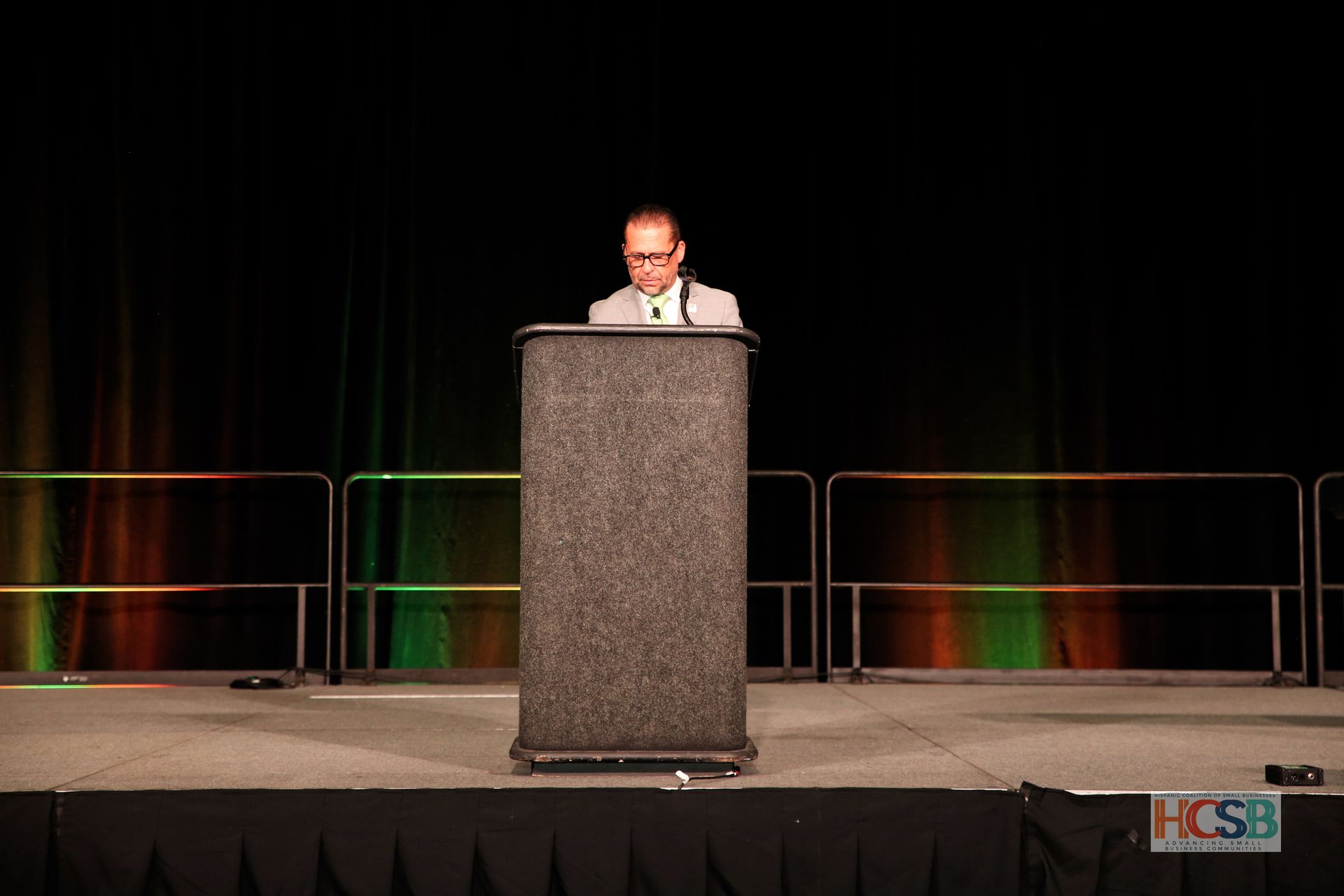 A man stands at a podium in front of a hcsb banner