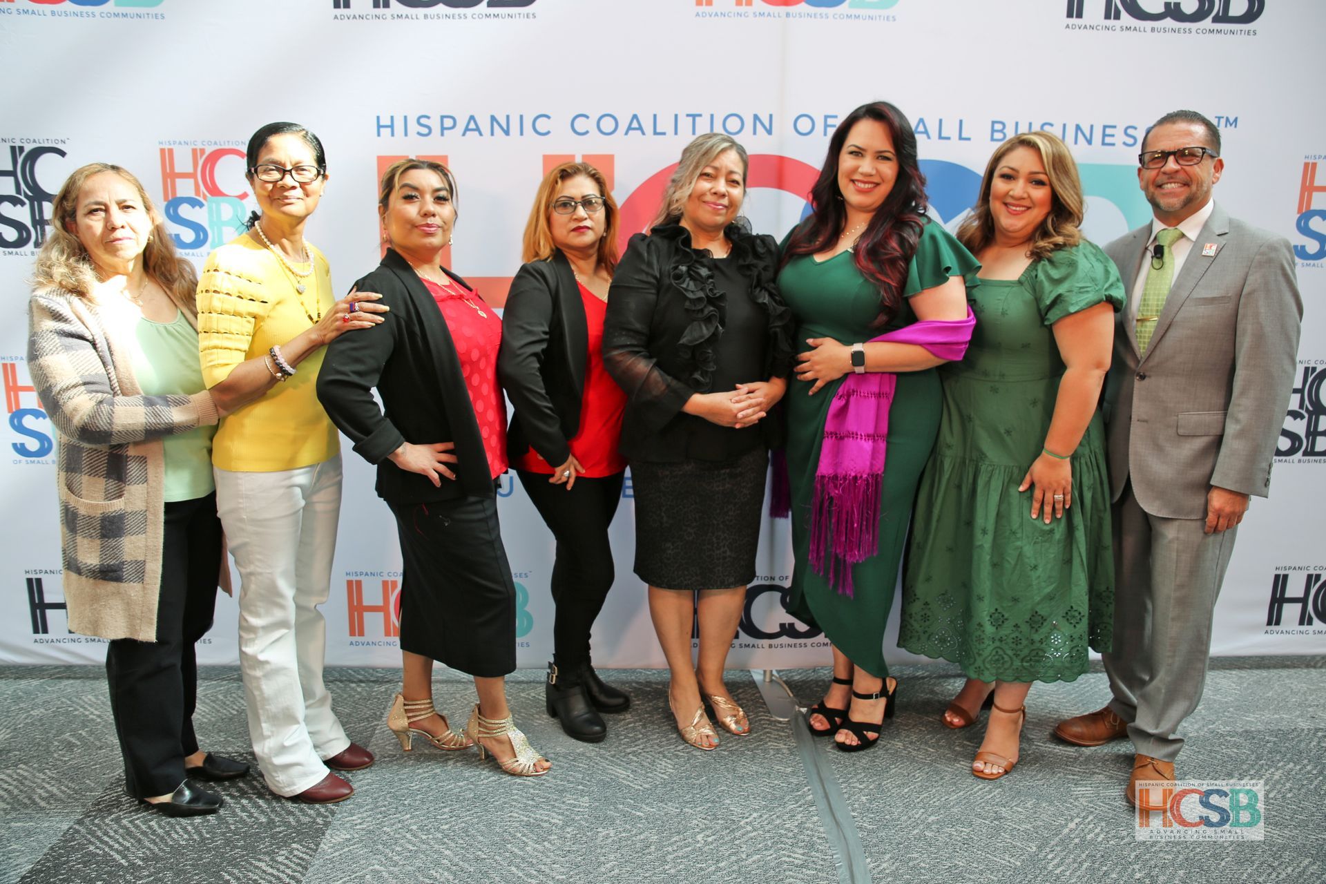 A group of people standing in front of a hispanic coalition of all businesses backdrop
